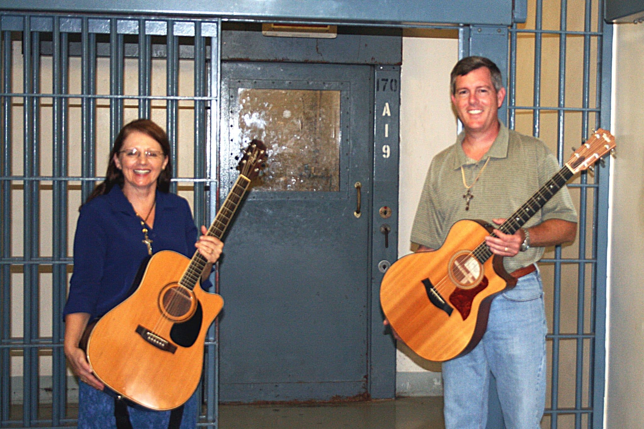 Eveline Nachtegaele and Kevin Cadenhead with guitars at a jail cell door during Loves Gate jail ministry