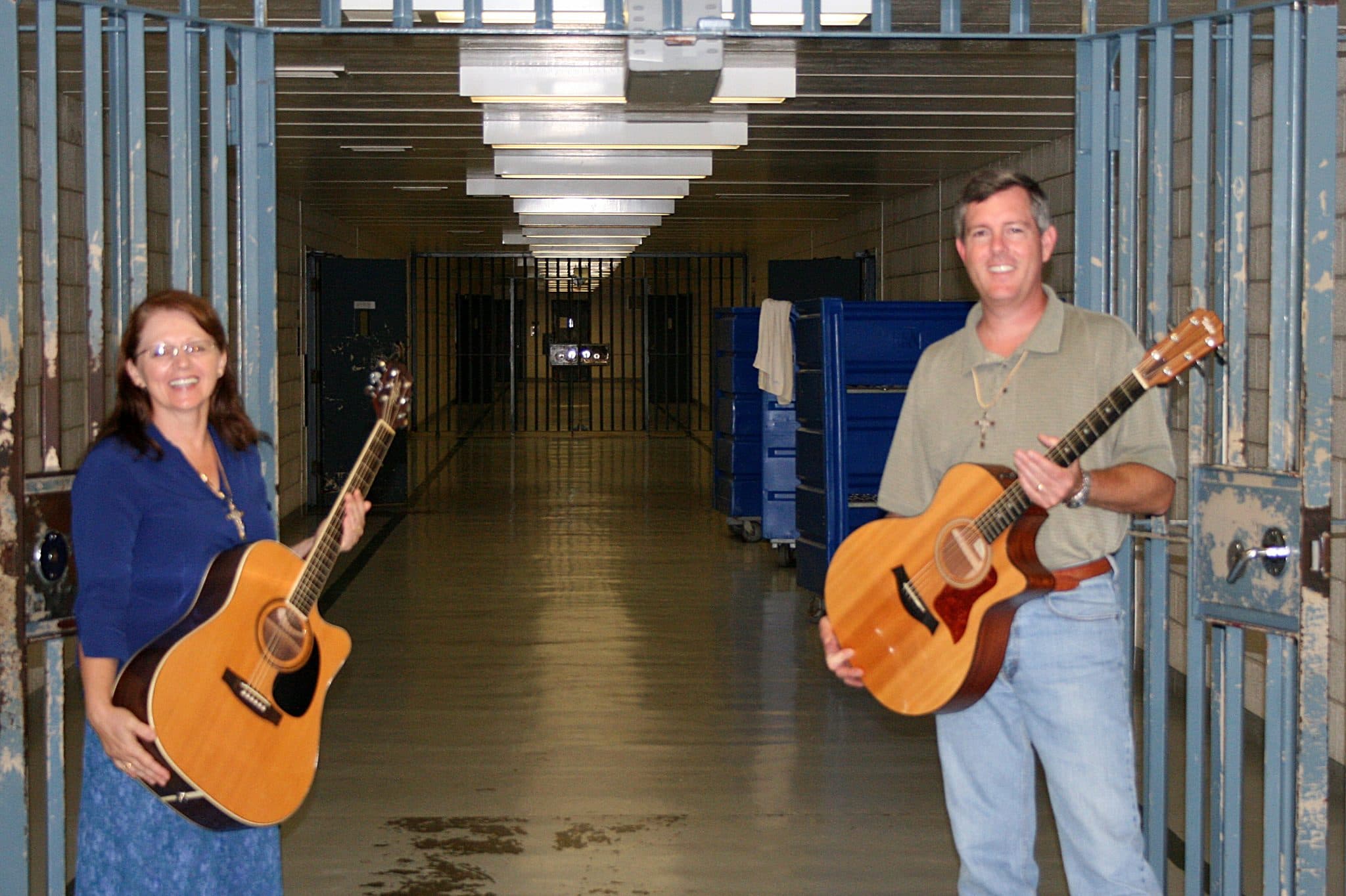Loves Gate musicians carrying guitars through a jail corridor